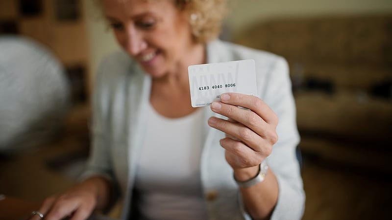 A plastic identification card lying on a dark surface beside a magnifying glass, with small printed fields visible.