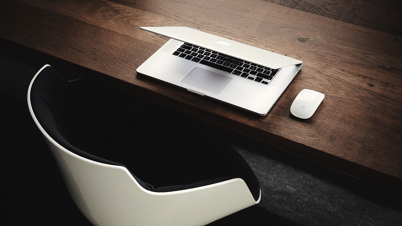 An empty chair pushed back from a long conference table, with a half-full water glass and a closed notebook.